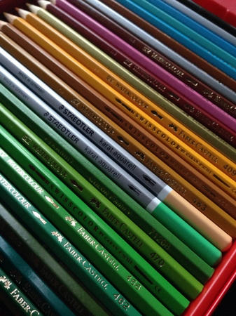 ファーバーカステル・ステッドラー・SWISS COLORの水彩色鉛筆が、25本程度赤い容器に整然と格納されている写真。写真は色鉛筆のすぐ近くで撮影されており、「STAEDTLER」「FABER-CASTELL」「SWISS COLOR」などのロゴが各色鉛筆に印字されているのが見える。