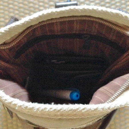 茶色のシザーバッグの一番大きなポケットを開いた画像。黒い財布と水色のラインマーカーがシザーバッグの中に入っている。シザーバッグの裏地はは茶色にベージュのストライブ柄