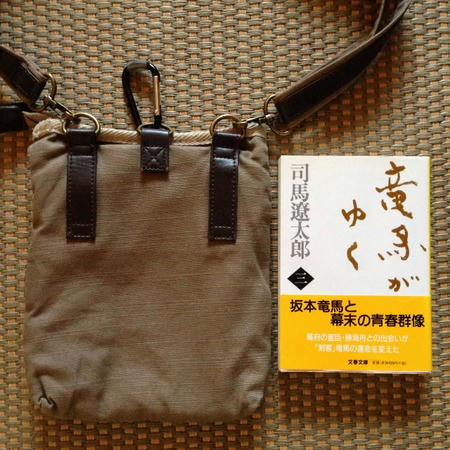 茶色のシザーバッグを床に置き背面から写した画像。左にシザーバッグ、右に司馬遼太郎「竜馬がゆく」三巻の文庫本を平置きしている